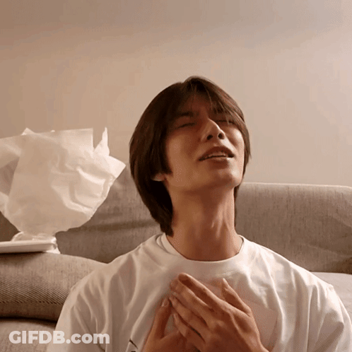 A Man In A White Shirt Is Sitting On A Couch With His Eyes Closed GIF