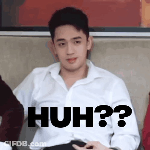 A Man In A White Shirt Is Sitting On A Couch With The Words Huh Written On His Chest GIF