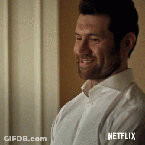 A Man In A White Shirt Is Smiling And Looking At Something . GIF