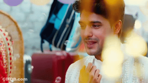 A Man In A White Shirt Is Smiling In Front Of A Bride In A Red Dress . GIF