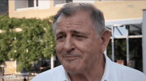 A Man In A White Shirt Is Smiling In Front Of A Building That Says Hd On The Bottom GIF