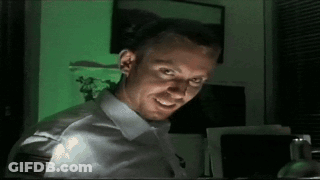 A Man In A White Shirt Is Smiling In Front Of A Green Screen GIF