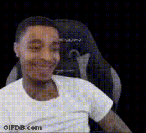 A Man In A White Shirt Is Smiling While Sitting In A Chair . GIF
