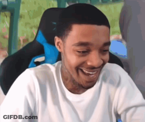 A Man In A White Shirt Is Smiling While Sitting In A Gaming Chair . GIF