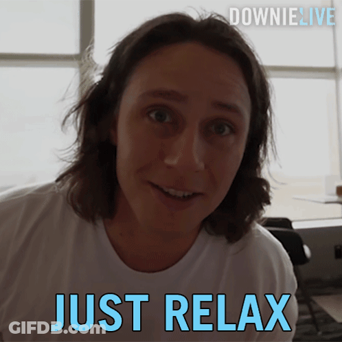 A Man In A White Shirt Is Smiling With The Words Just Relax Below Him GIF