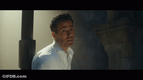 A Man In A White Shirt Is Standing In A Dark Room With His Mouth Open GIF