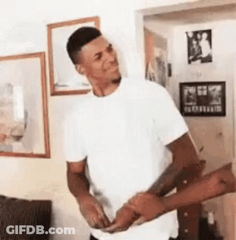 A Man In A White Shirt Is Standing In A Living Room Holding A Woman 'S Hand . GIF