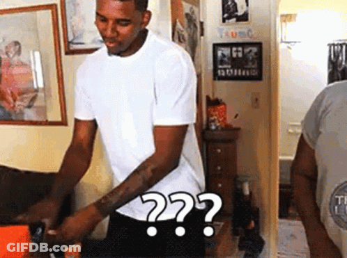A Man In A White Shirt Is Standing In A Room With A Question Mark . GIF