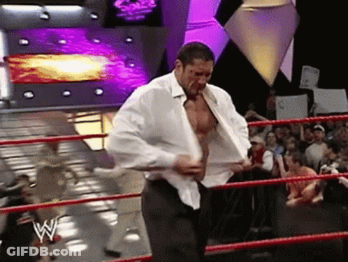 A Man In A White Shirt Is Standing In A Wrestling Ring With The Letter W On The Ring GIF