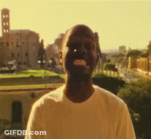A Man In A White Shirt Is Standing In Front Of A Castle GIF