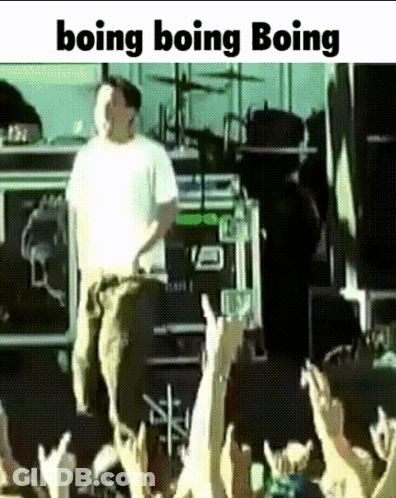 A Man In A White Shirt Is Standing In Front Of A Crowd With The Words Boing Boing Boing Written Below Him GIF
