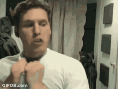 A Man In A White Shirt Is Standing In Front Of A Door GIF