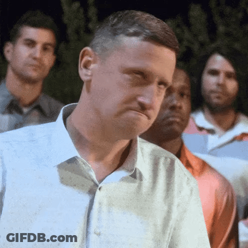 A Man In A White Shirt Is Standing In Front Of A Group Of Men GIF