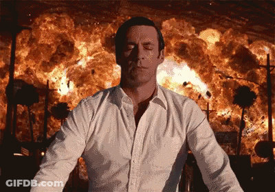 A Man In A White Shirt Is Standing In Front Of A Large Explosion GIF