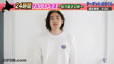 A Man In A White Shirt Is Standing In Front Of A Sign That Says 24 時間 GIF