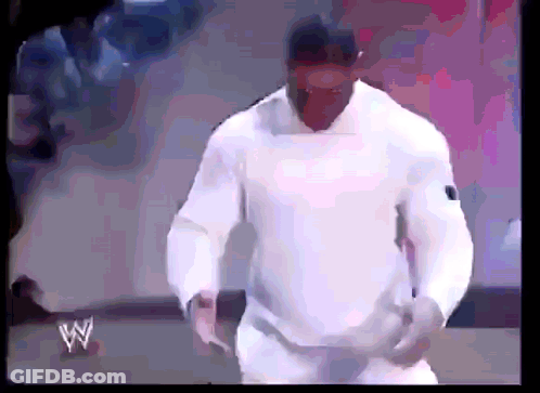 A Man In A White Shirt Is Standing In Front Of A Sign That Says W On It GIF