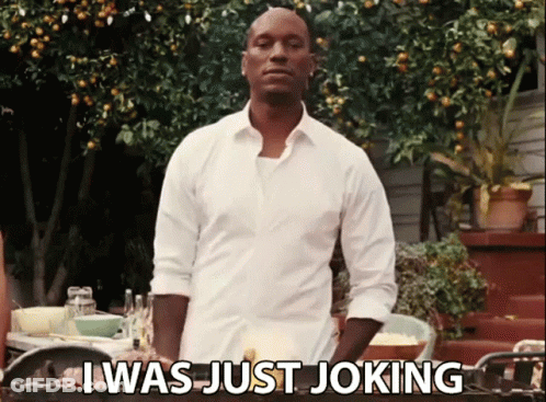 A Man In A White Shirt Is Standing In Front Of A Table And Says " I Was Just Joking " GIF