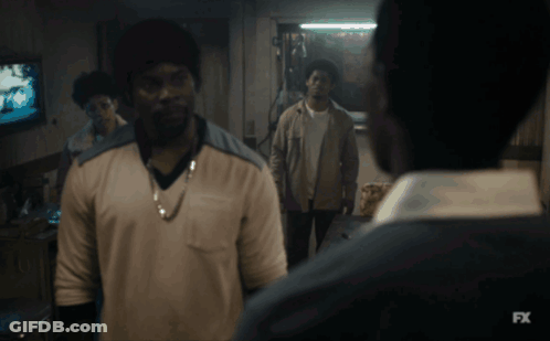 A Man In A White Shirt Is Standing In Front Of A Tv Screen That Says Fx GIF