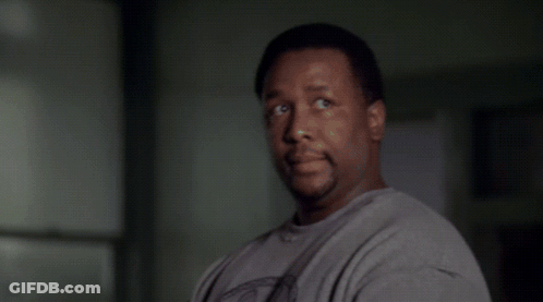 A Man In A White Shirt Is Standing In Front Of A Window GIF
