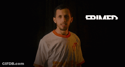 A Man In A White Shirt Is Standing In The Dark With The Word Frimed Behind Him GIF