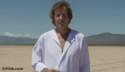A Man In A White Shirt Is Standing In The Desert GIF