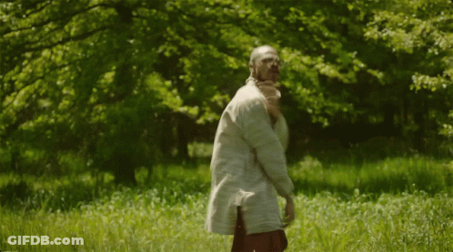A Man In A White Shirt Is Standing In The Grass GIF