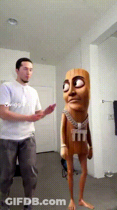 A Man In A White Shirt Is Standing Next To A Cartoon Character With A Shirt That Says M And M On It GIF