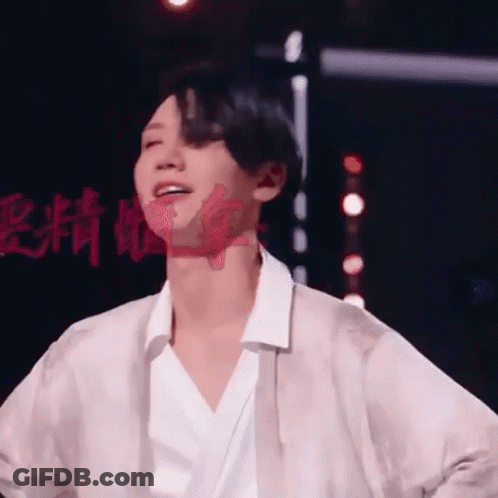 A Man In A White Shirt Is Standing On A Stage With His Hands In His Pockets . GIF