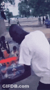 A Man In A White Shirt Is Standing On A Street With A Tiktok Logo On The Bottom Left GIF