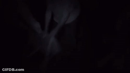 A Man In A White Shirt Is Standing On A Suitcase In A Room GIF
