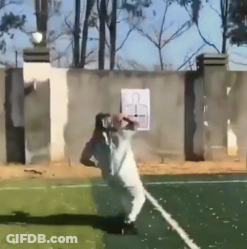 A Man In A White Shirt Is Standing On A Tennis Court With A Target In The Background .. GIF