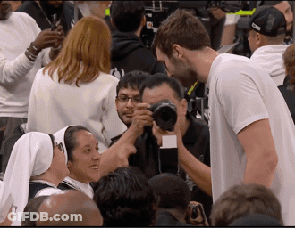 A Man In A White Shirt Is Taking A Picture Of A Woman GIF