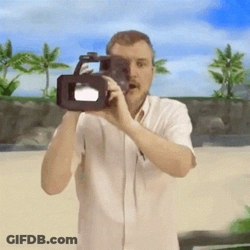 A Man In A White Shirt Is Taking A Picture With A Video Camera GIF