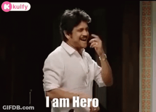 A Man In A White Shirt Is Talking On A Cell Phone While Standing In A Room . GIF
