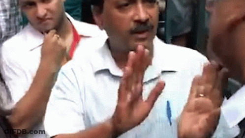 A Man In A White Shirt Is Talking To Another Man In A Crowd With His Hands Outstretched . GIF