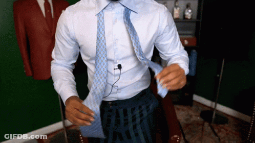 A Man In A White Shirt Is Tying A Tie GIF