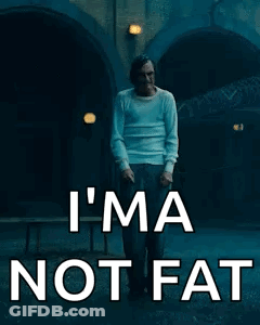 A Man In A White Shirt Is Walking Down A Street With The Words `` I 'M Not Fat '' Written On It . GIF