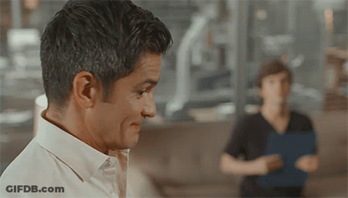A Man In A White Shirt Looks At Another Man GIF
