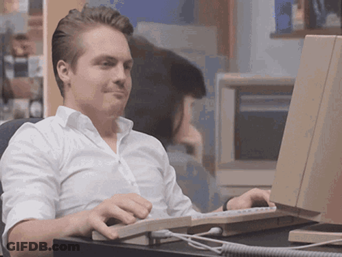 A Man In A White Shirt Sits In Front Of A Computer GIF