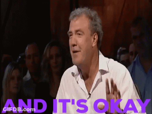 A Man In A White Shirt Stands In Front Of A Crowd With The Words And It 'S Okay Behind Him GIF