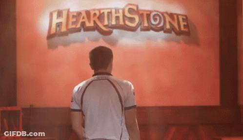 A Man In A White Shirt Stands In Front Of A Hearthstone Sign GIF