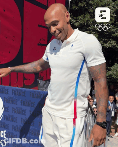 A Man In A White Shirt Stands In Front Of A Sign That Says France GIF