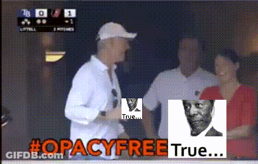 A Man In A White Shirt Stands In Front Of A Sign That Says #Opacyfreetrue GIF