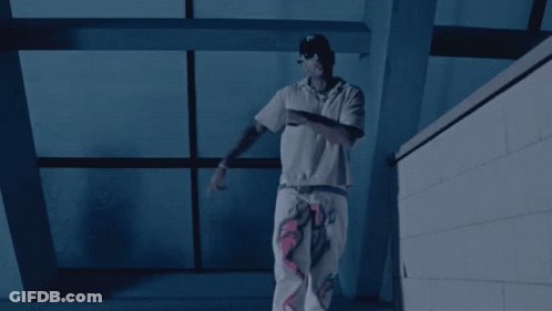 A Man In A White Shirt Stands In Front Of A Window GIF