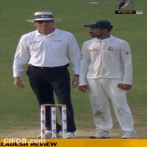 A Man In A White Shirt That Says Kcc Stands Next To A Man In A Black Hat GIF