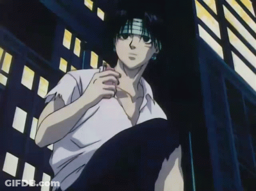 A Man In A White Shirt With A Bandana On His Head Is Sitting In Front Of A Building GIF