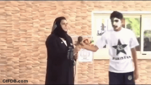 A Man In A White Shirt With A Black Star On It Is Standing Next To A Woman In A Black Hijab . GIF
