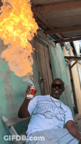 A Man In A White Shirt With A Crocodile On It Is Holding A Can Of Spray Paint GIF