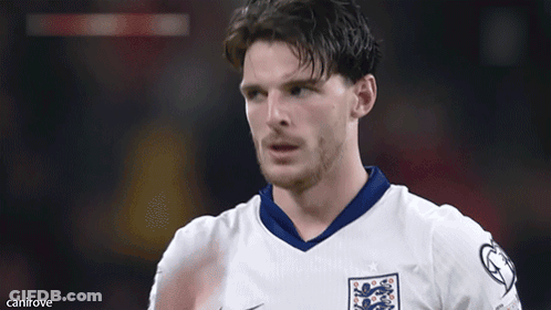 A Man In A White Shirt With A Lion On It Holds His Hand To His Forehead GIF