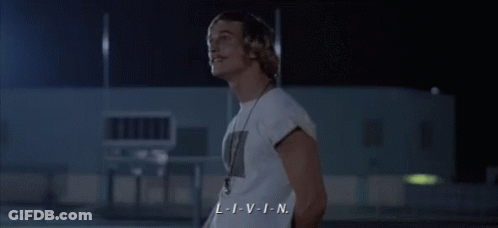 A Man In A White Shirt With A Necklace Around His Neck Says L-I-V-I-N GIF